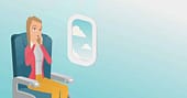 How to get over fear of flying featured image: anxious woman sitting in an airplane seat
